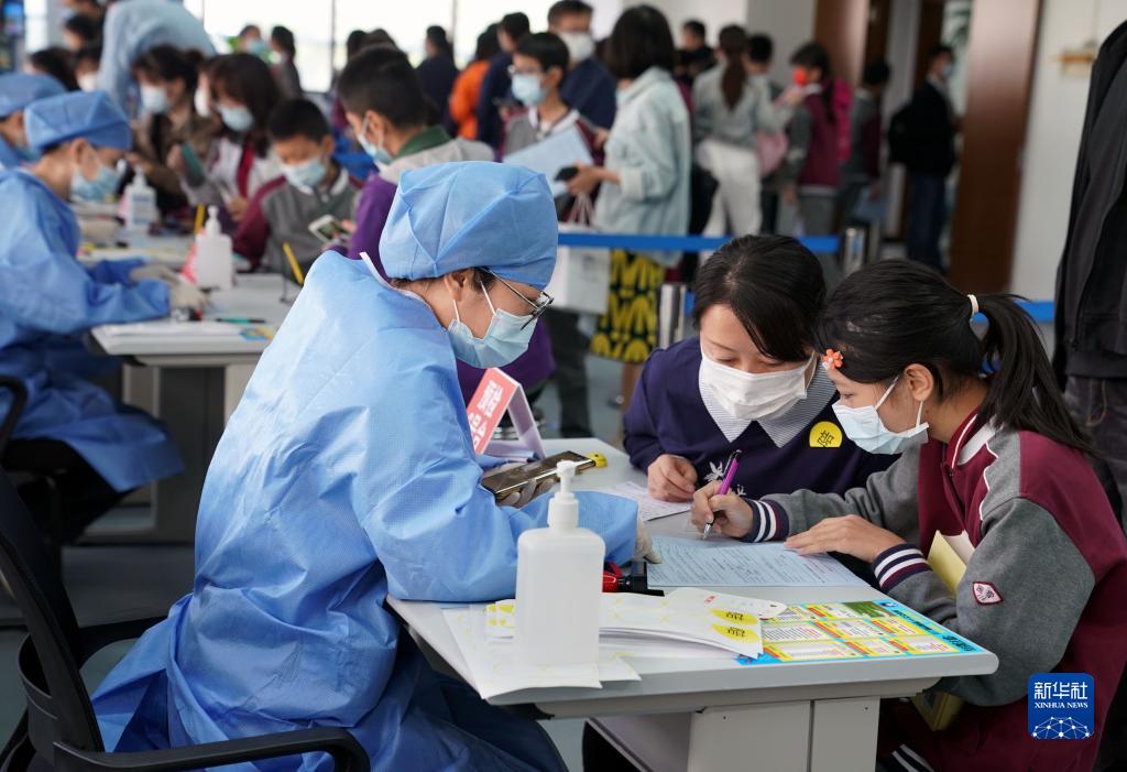 预约接种的6至11岁学生在家长陪同下签写接种知情同意书